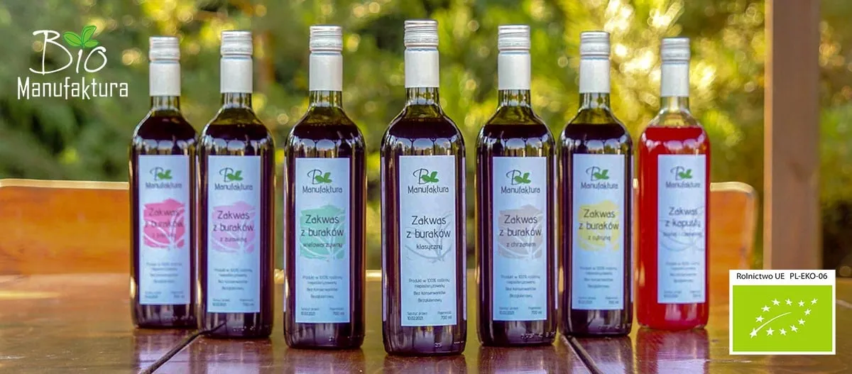 Siedem butelek zakwasów Bio Manufaktura na stole w ogrodzie